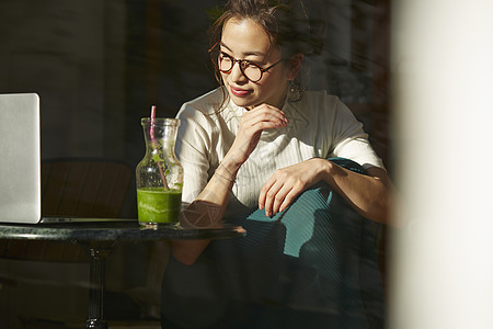 女人坐在窗边的桌上喝奶昔工作图片