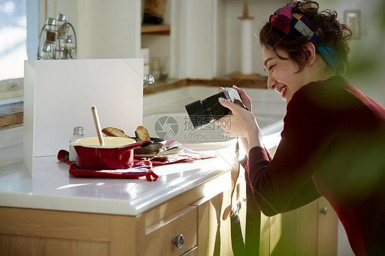 在料理台上给刚刚做好的饭拍照的女人图片