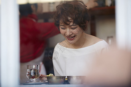 坐在桌边笑着吃饭的女人图片