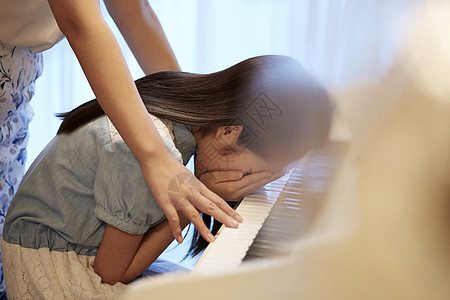 老师看着钢琴前哭泣的女孩图片