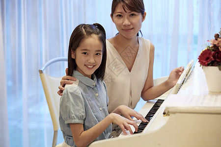 钢琴老师和练琴的女孩一起看着镜头微笑图片