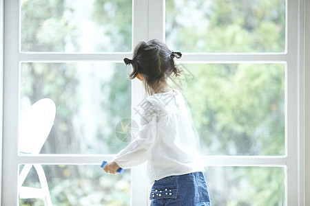 拿着玩具站在窗边的小女孩图片