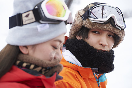 男性和女性参加俱乐部滑雪活动的情侣在雪地聊天背景