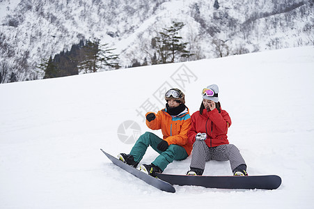 参加俱乐部滑雪活动的情侣在雪地聊天图片