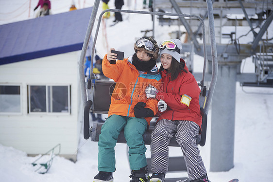 参加俱乐部滑雪活动的情侣在缆车上自拍图片
