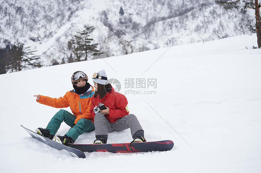 参加俱乐部滑雪活动的情侣在雪地聊天图片