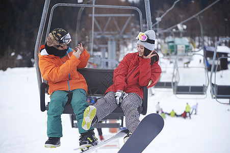 参加俱乐部滑雪活动的情侣在缆车上拍照图片