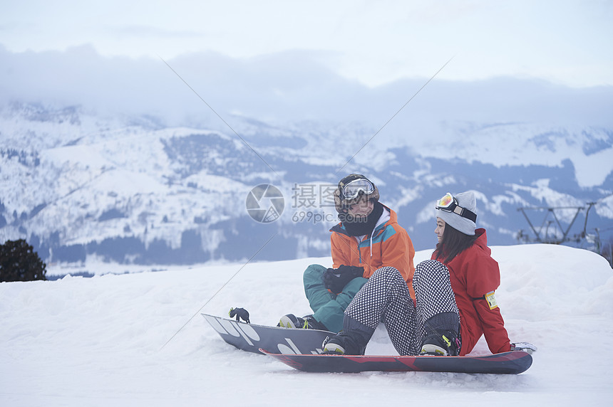 参加俱乐部滑雪活动的情侣在雪地聊天图片