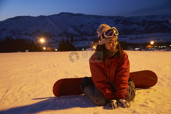 参加俱乐部滑雪活动的女人坐在雪地上微笑图片