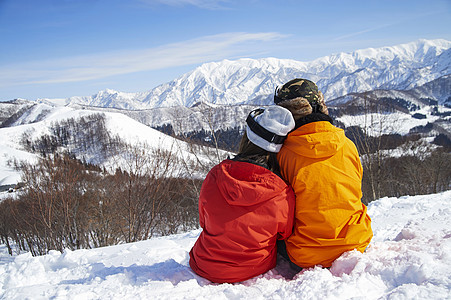 参加俱乐部滑雪活动的情侣在雪地聊天图片