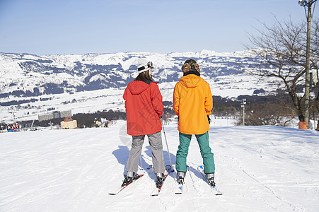 参加俱乐部滑雪活动的情侣在雪地站着图片