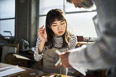 在看师傅装订书本的年轻女孩图片