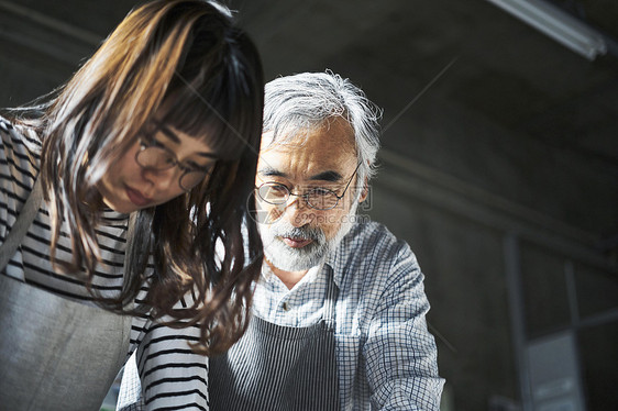 手工艺人在指导学生装订书籍图片