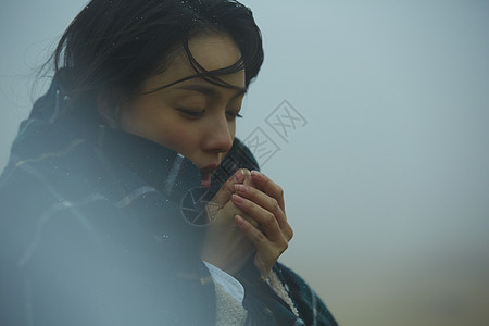 握紧双手哈气取暖的女性图片素材