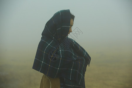 站在迷雾中包裹着围巾的女性图片