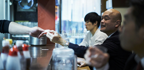 递给服务员食品券坐着等待食物上桌的男人图片