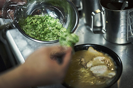 厨师给拉面加上配料背景图片