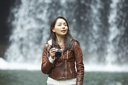 瀑布旁拿着相机的年轻女性图片