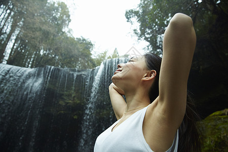 站在小溪边享受瀑布的女人在舒展身体图片