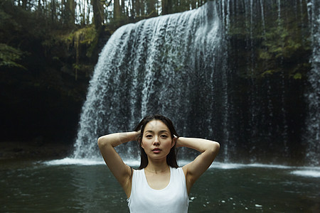 站在小溪边享受瀑布的女人看着镜头图片