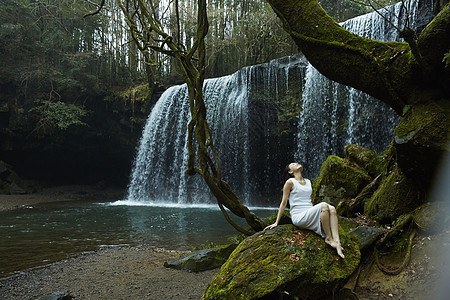 坐在岩石上的白裙女子图片
