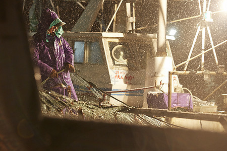 下雨天穿着雨披的渔夫拉着渔网图片