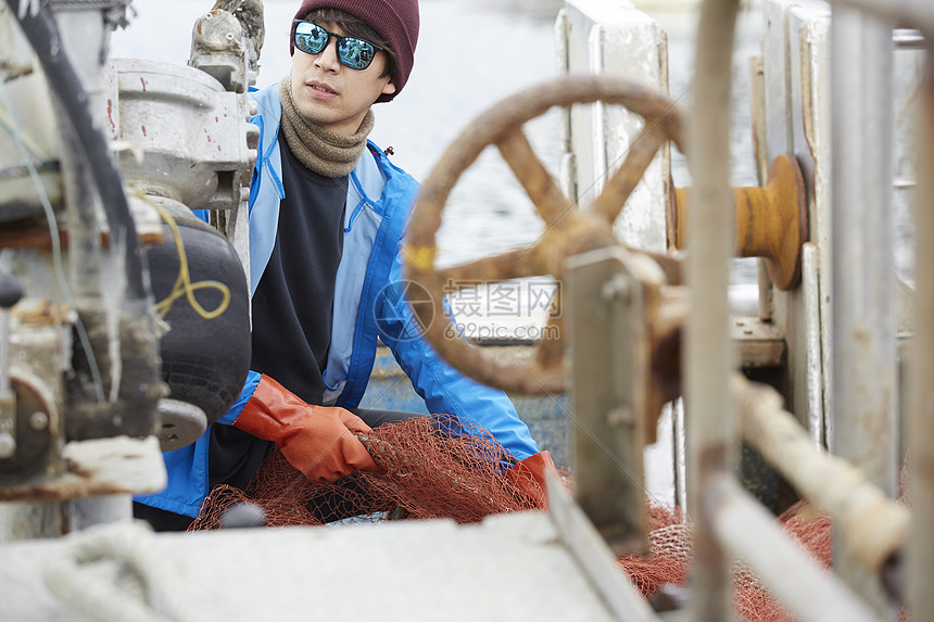 正在船上工作的年轻渔民形象图片