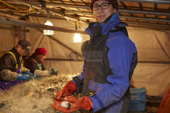 年轻的渔民手拿海鲜微笑图片