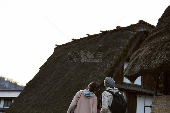 来采风的两个女人在茅草屋前驻足图片