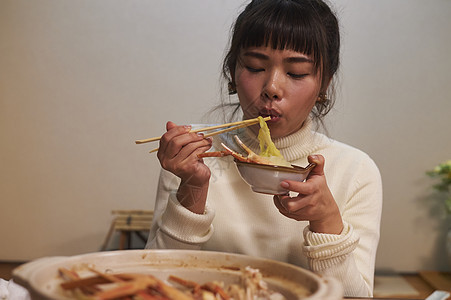 吃松叶蟹平底锅的妇女图片