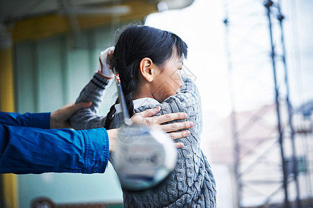 调整指导女孩挥动球杆姿势的教练图片