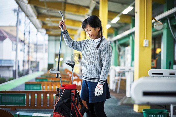 高尔夫球带里拿出高尔夫球杆的女孩图片