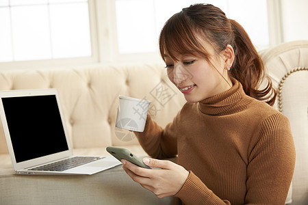 居家喝茶看手机的女人图片