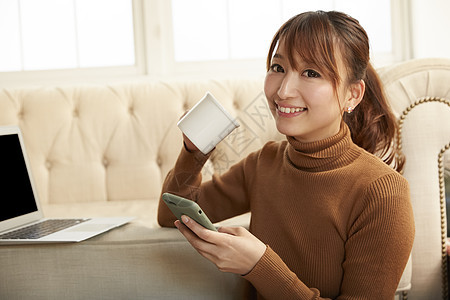 居家坐在电脑面前拿着手机的女孩图片