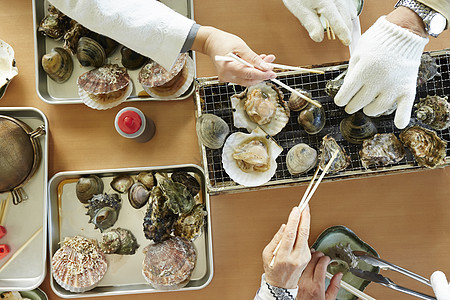 游客吃海鲜烤贝类特写图片