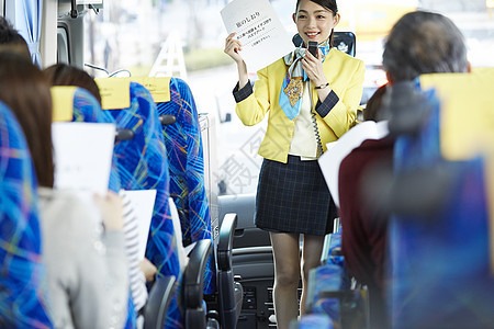巴士上为旅客讲解旅行手册的导游图片