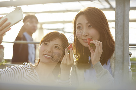 拿着草莓自拍的年轻女性背景图片