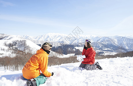  坐在雪地里的一对情侣图片