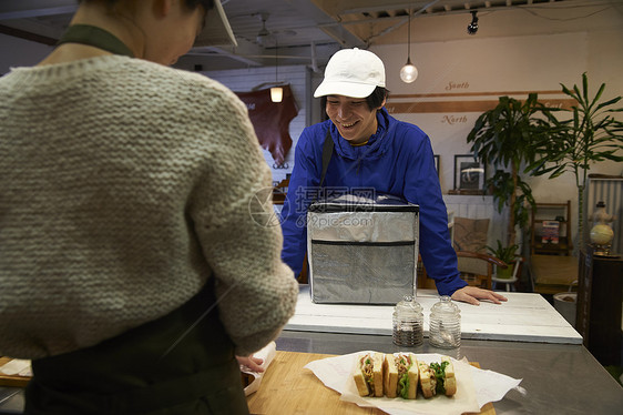 在等待餐厅服务员打包食物的外卖员图片