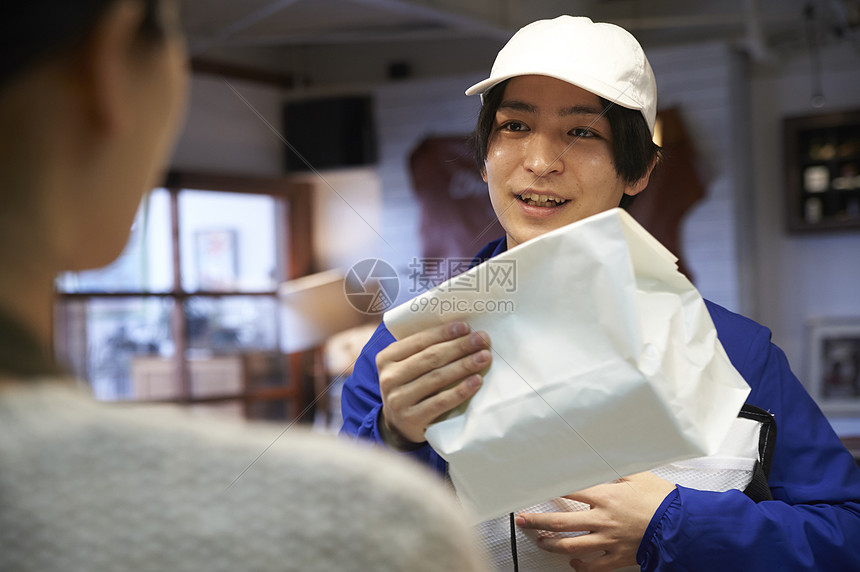 店员递包装好的外卖给配送员图片