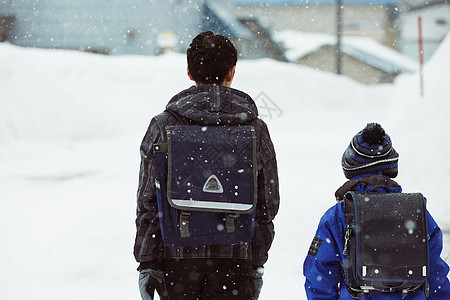 下雨天背着书包雪地里行走的学生背影图片