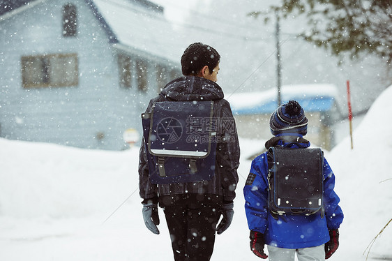 下雨天背着书包雪地里行走的学生背影图片