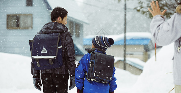 下雨天背着书包雪地里行走的学生背影图片