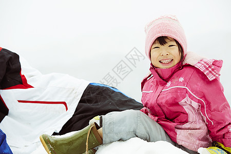 坐在雪地里微笑的小女孩图片