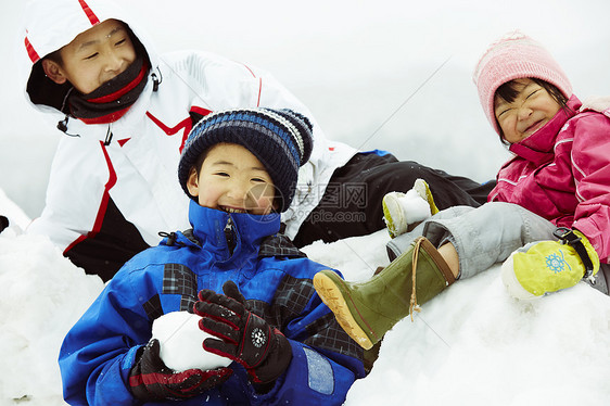 坐在雪地里捏着冰球的孩子们图片