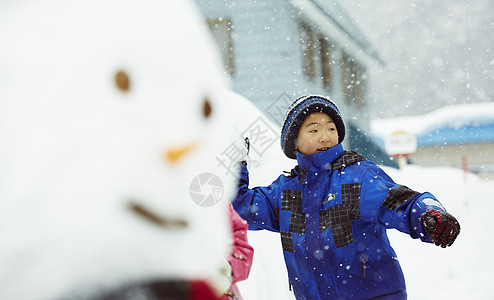 雪地里拿着雪球投掷的小男孩图片