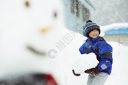 抱着巨大雪球的小男孩图片