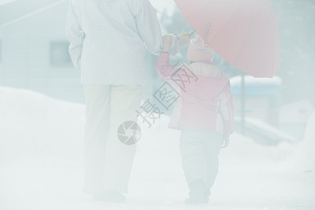 雪天撑着雨伞散步的母女图片