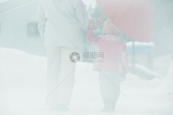 雪天撑着雨伞散步的母女图片