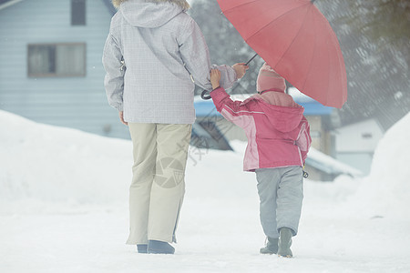 雪天撑着雨伞散步的母女背影图片